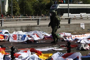 A bomb-disposal expert walks near victims' bodies covered with banners and flags, at the site of twin explosions near the main train station in Turkey's capital Ankara, on October 10, 2015. At least 86 people were killed on October 10 in the Turkish capital Ankara when bombs set off by two suspected suicide attackers ripped through leftist and pro-Kurdish activists gathering for an anti-government peace rally, the deadliest attack in the history of modern Turkey. AFP PHOTO / ADEM ALTAN